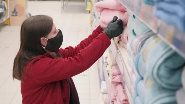 Wooman v masce a rukavicích proti viru kupuje froté, růžový sprchový ručník v obchodě - Záběry, video