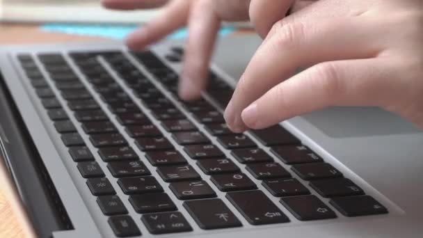 Trabajando con un portátil de cerca. La muchacha escribe el texto en el teclado del ordenador portátil, trabaja, se comunica. Teclado y dedos se cierran - Metraje, vídeo