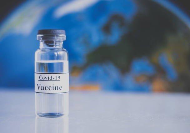 コピースペースと地球上の地球の背景にコロナウイルスワクチン。ワクチン液とガラスアンプル。予防,予防接種とcovidからの治療-19, sars-cov-2.パンデミックの概念との戦い - 写真・画像