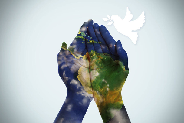 El planeta Tierra pintó manos humanas sobre un fondo claro. Día Internacional de la Paz - Foto, imagen