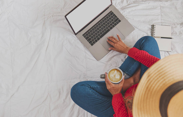 Portret Latynoski pijącej gorącą kawę, używającej laptopa, oglądającej wideo, wolnej przestrzeni. Siedzisz na kanapie i relaksujesz się w przytulnym domu. Koncepcja twórczej pracy w domu. Skupienie selektywne. - Zdjęcie, obraz