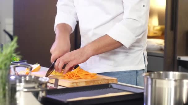 Lo chef taglia il pepe giallo per insalata con coltello affilato. chef maschio prepara insalata in casa cucina. Cucina deliziosa pasto nella cucina del ristorante. Preparazione degli ingredienti. Cibo sano ogni giorno - Filmati, video