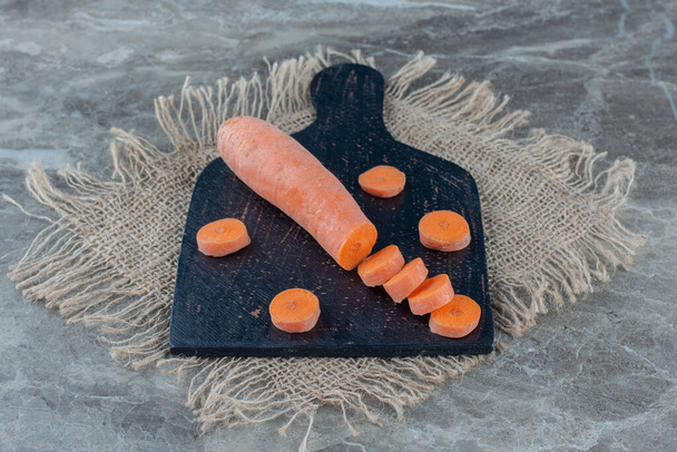 Carrot slices on a cutting board, on the trivet, on the marble background. High quality photo - Photo, Image