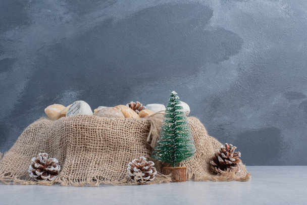 Finom sütik kötegelt egy darab ruhát közepette karácsonyi dekorációk márvány háttér. Kiváló minőségű fénykép - Fotó, kép
