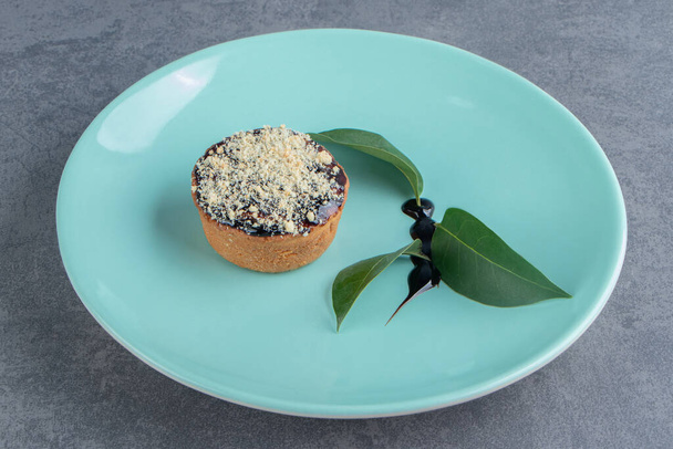 A piece of creamy cake with leaves on a green plate. High quality photo - Photo, Image