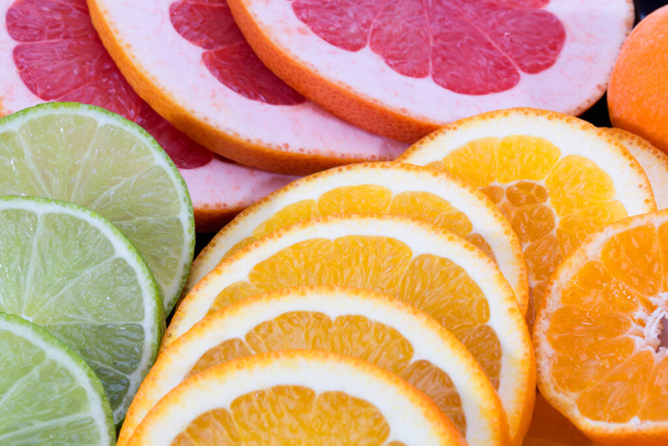 Fondo de rodajas de fruta de pomelo rojo, lima verde y mandarina, primer plano - Foto, Imagen