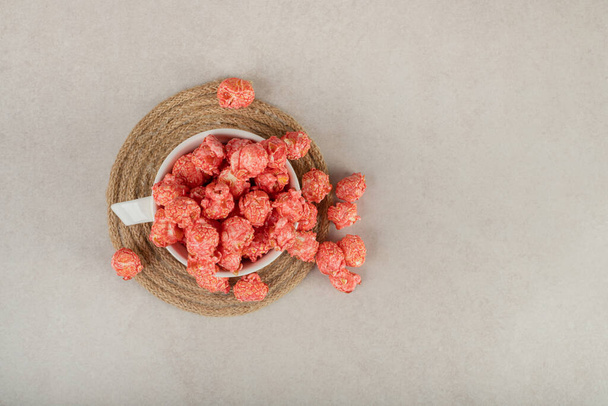 Tazza da tè su un rivetto traboccante di popcorn rossi su sfondo di marmo. Foto di alta qualità - Foto, immagini