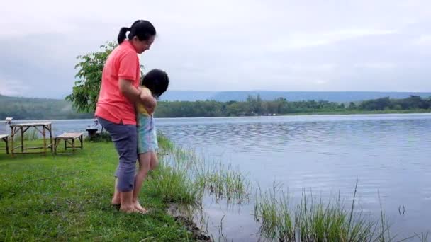 Anya jól érzi magát a gyerekével. Boldog ázsiai lány szórakozik a tónál. Boldog család töltenek időt együtt kívül zöld természet. Utazás nyaralni.  - Felvétel, videó