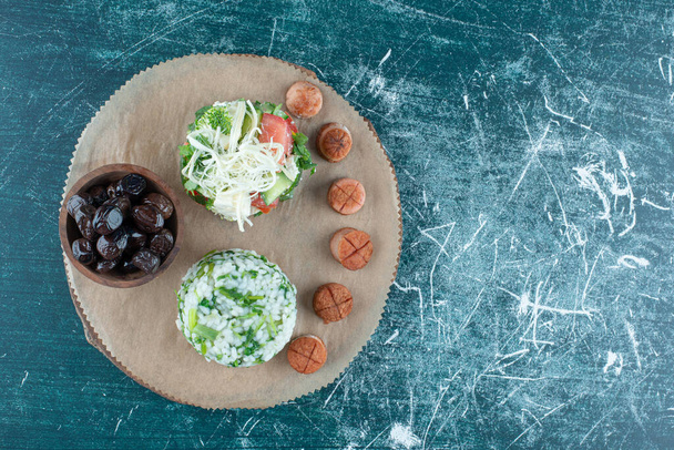Snack tábla salátával és kolbásszal, kék háttérrel. Kiváló minőségű fénykép - Fotó, kép