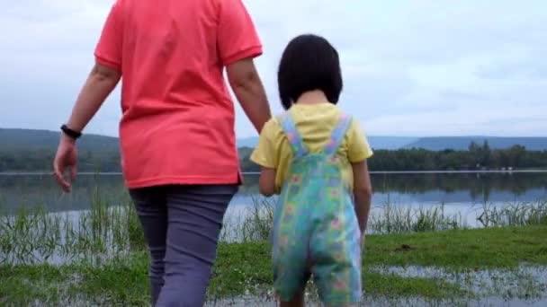 Anya jól érzi magát a gyerekével. Boldog ázsiai lány szórakozik a tónál. Boldog család töltenek időt együtt kívül zöld természet. Utazás nyaralni. - Felvétel, videó