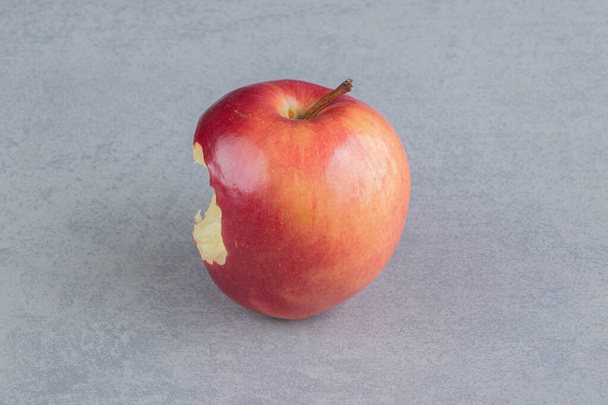 Кусатое яблоко отображается на мраморном фоне. Высокое качество фото - Фото, изображение