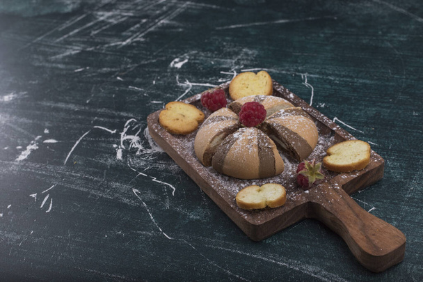 domácí sušenky na dřevěné desce s bobulemi a cukrovým práškem - Fotografie, Obrázek