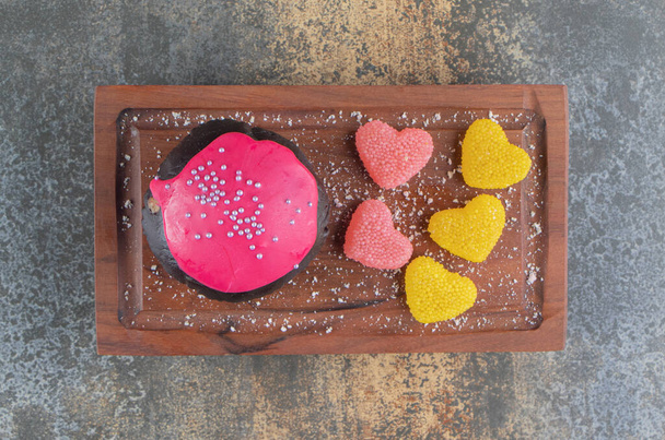 Biscuit au chocolat avec glaçure rose et bonbons sur carton en bois. Photo de haute qualité - Photo, image