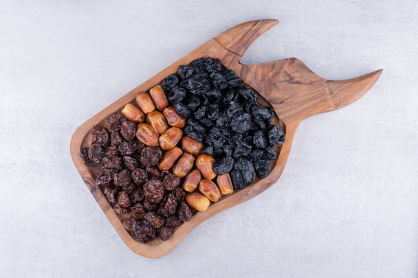 Сухие фрукты с финиками и вишней на деревянном блюде. Высокое качество фото - Фото, изображение