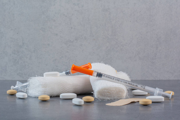 Band aid plasters, pills, bandage and syringe on marble surface. High quality photo - Photo, Image
