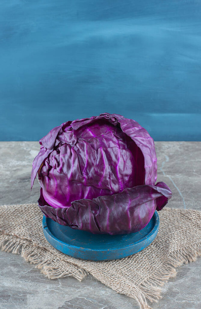 Col púrpura en la placa de madera, en el trivet, sobre el fondo de mármol. Foto de alta calidad - Foto, Imagen