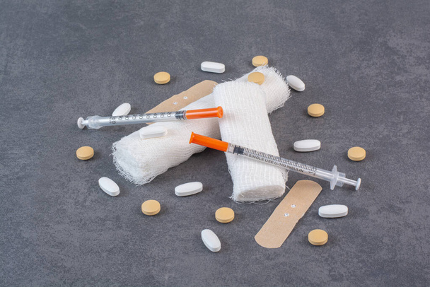 Band aid plasters, pills, bandage and syringe on marble surface. High quality photo - Photo, Image