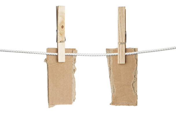два рвані шматки картону, що звисають на одній прищіпки, ізольовані
 - Фото, зображення