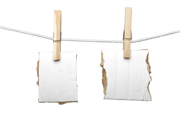 zwei zerrissene Kartonstücke, die an einer Wäscheklammer hängen, isol - Foto, Bild