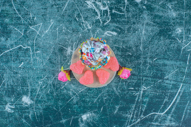 Ein Cupcake, Marmeladen und Blumenkronen gebündelt auf blauem Hintergrund. Hochwertiges Foto - Foto, Bild