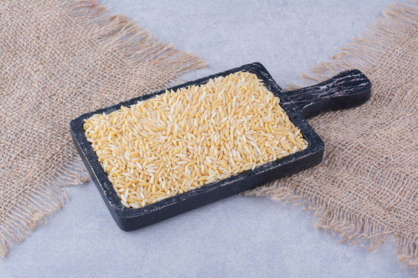 Bandeja negra gastada provista de arroz integral sobre fondo de mármol. Foto de alta calidad - Foto, Imagen