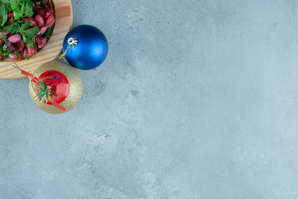 Vinegret serveert op een houten schotel en twee kerstballen op marmeren ondergrond. Hoge kwaliteit foto - Foto, afbeelding
