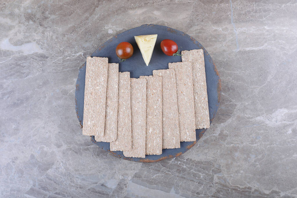 Bir yığın cips, domates, ahşap tahtada, mermer zeminde peynir. Yüksek kalite fotoğraf - Fotoğraf, Görsel