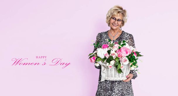 Journée internationale de la femme. Belle femme mûre heureuse senior, tient bouquet de fleurs sur fond rose. La génération des femmes. 8 mars - Journée de la femme. - Photo, image