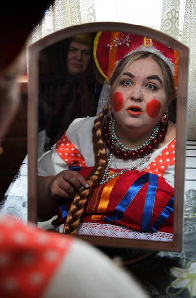Μια γυναίκα ντυμένη ρώσικη ομορφιά μπροστά στον καθρέφτη. Cosplay για το παραμύθι Morozko. - Φωτογραφία, εικόνα