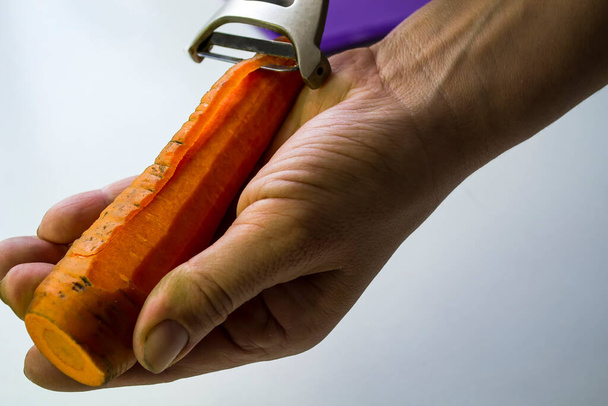 A womans hand.Brushing fresh carrots close-up. - Photo, Image