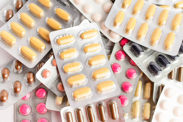 Primer plano de diferentes píldoras medicinales, tabletas y vitaminas aisladas sobre fondo blanco, fotografía farmacéutica tomada con enfoque suave - Foto, imagen