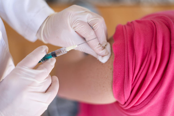 Covid vacine injectie door arts in het ziekenhuis.Arts maken injectie vaccinatie patiënt om pandemie van de ziekte te voorkomen, griep of influenza virus in de kliniek - Foto, afbeelding