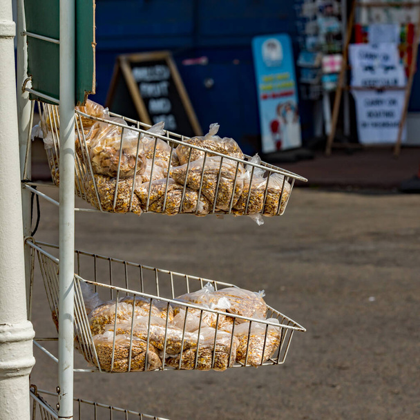 Horning, Norfolk 'taki bir dükkanın önünde üzerinde kuş yemi bulunan şeffaf plastik poşetler. Kuş yemi turistlere, tatilcilere ve çeşitli türlerden oluşan yerel kuş yaşamını beslemek isteyen ziyaretçilere satılıyor.  - Fotoğraf, Görsel