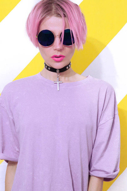Blondes Mädchen in lässigem Sommerlook und stylischem Accessoire mit Kreuzverschluss und Sonnenbrille. Trendiges Alltagsoutfit im Detail - Foto, Bild
