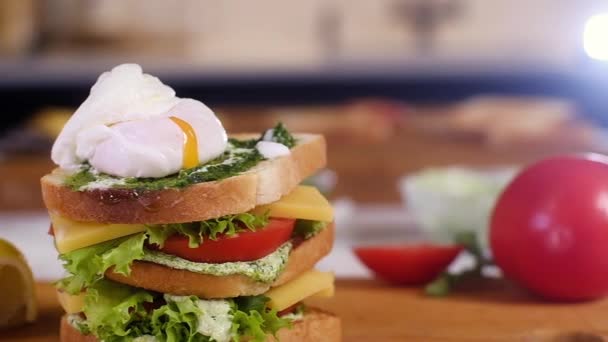 Cooking delicious natural sandwich for Breakfast or lunch in kitchen home on wooden Board. concept of healthy eating. Fast food. Burger with crusty bread toast and poached egg. Making cheese sandwich - Footage, Video
