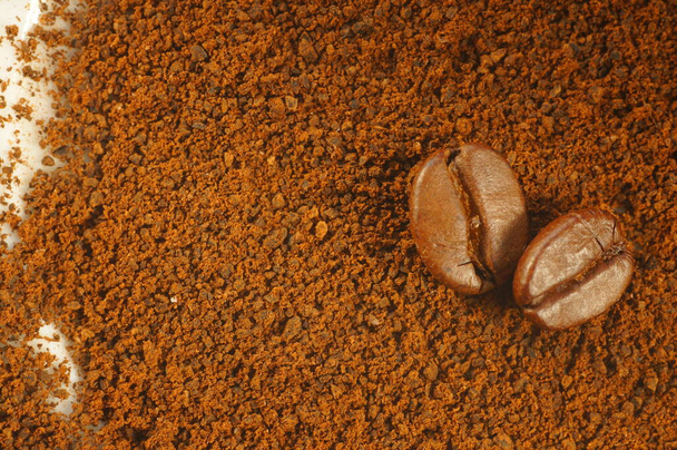 Coffee beans on brown and white background. Coffee beans and ground coffee. Blurred white parts of the background. Background for text or graphic. - Photo, Image