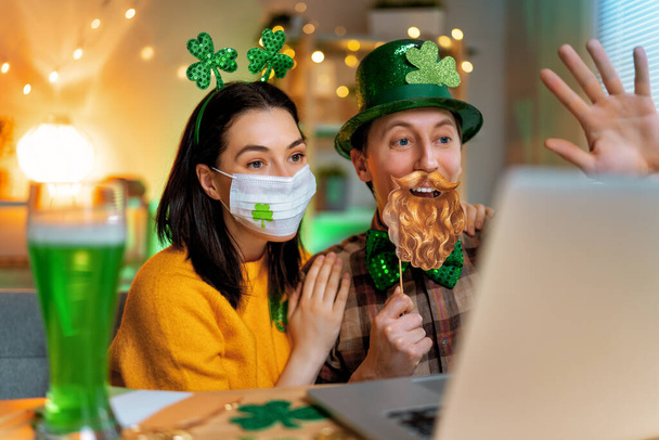 Happy family couple celebrating St. Patrick's Day with their friends by online at home. - 写真・画像
