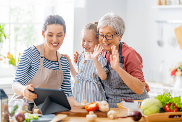 Healthy food at home. Happy family in the kitchen. Grandma, mother and child daughter are preparing vegetables. - Foto, Bild