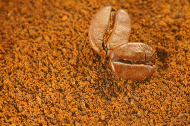 Geröstete Kaffeebohnen - über gebrauchten gemahlenen Kaffee gelegt. Nahaufnahme von Kaffeebohnen mit verschwommenem Hintergrund. Braune Farbe, viele sichtbare Details. - Foto, Bild