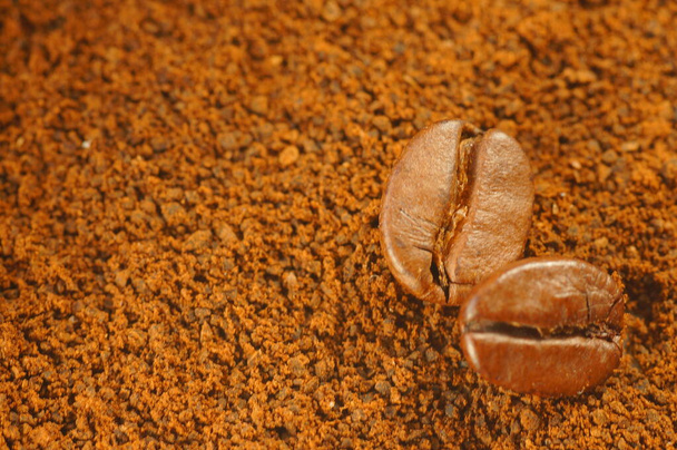 Grain de café torréfié - posé sur le café moulu utilisé. Gros plan sur grains de café avec fond flou. Couleur marron, beaucoup de détails visibles. - Photo, image