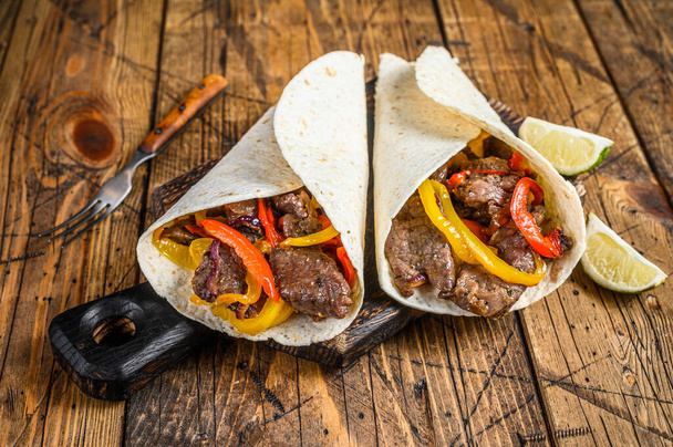 Fajitas Tortilla wrap with beef meat stripes, colored bell pepper and onions and salsa. Wooden background. Top view. - Photo, Image