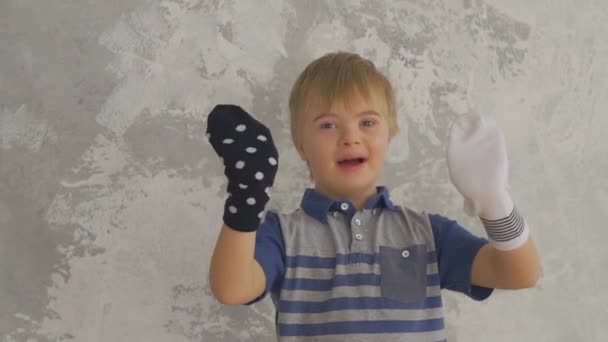 Pequeño niño con síndrome de Down divertirse con calcetines en las manos - Imágenes, Vídeo