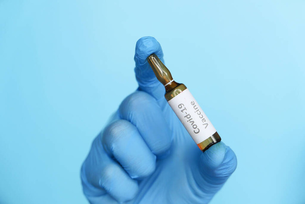 Hand in Hand in Latexhandschuhen mit Coronavirus-Impfstoff, mit Kopierraum  - Foto, Bild
