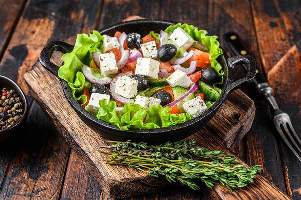 Ensalada griega con verduras frescas y queso feta en una sartén. Fondo de madera oscura. Vista superior. - Foto, imagen