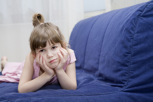 cute sceptical  little girl lying on sofa - Photo, Image