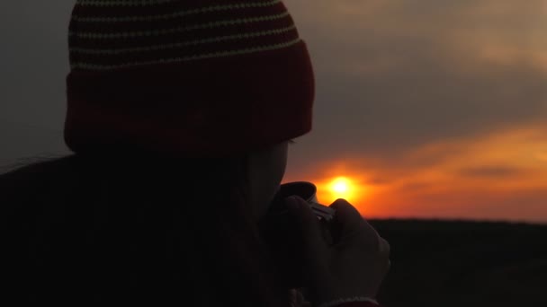 Woman Traveler tiene in mano una tazza di metallo con caffè caldo e guarda l'alba dalla montagna. Escursionista ragazza libera ammirando il paesaggio. Turista sta bevendo il tè da una tazza di sole. Viaggi, campeggio - Filmati, video