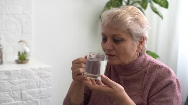 Starsza kobieta pije szklankę słodkiej wody. - Materiał filmowy, wideo