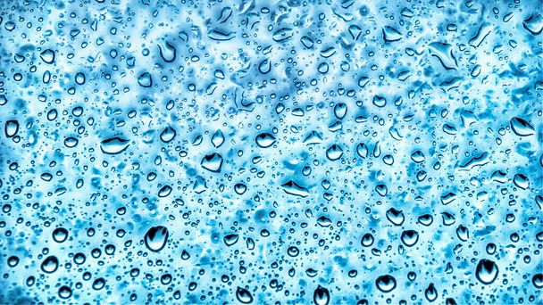 Waterdruppels en regendruppels op een glas. Waterzuiverheid en waterdicht. Donkerblauwe waterdruppels, regendruppels          - Foto, afbeelding