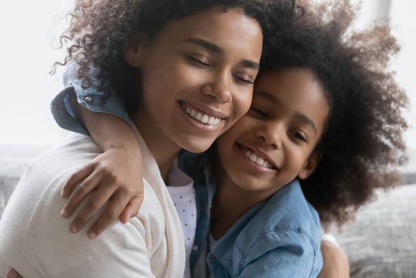Happy African American girl embracing her peaceful mom - Фото, зображення