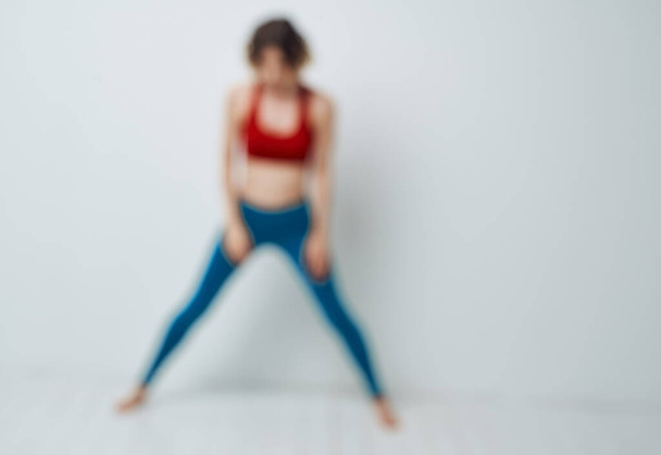 Žena v modrých džínách a červeném tričku dělá cvičení s předními ohyby - Fotografie, Obrázek